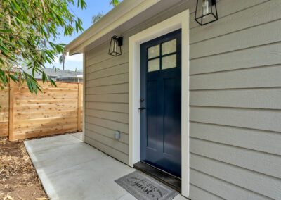 Snap-ADU-Carlsbad-Jefferson-St-2-bedroom-1-bathroom-750-sqft-exterior-shot-front-door-navy-door-doormat-lantern-lighting-woodeon-fence-bamboo